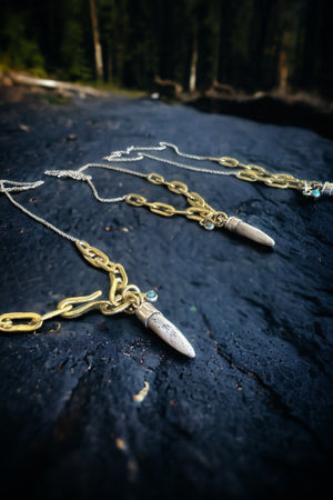 Three antler tipped necklaces made of large brass chain links are laying on black slate.